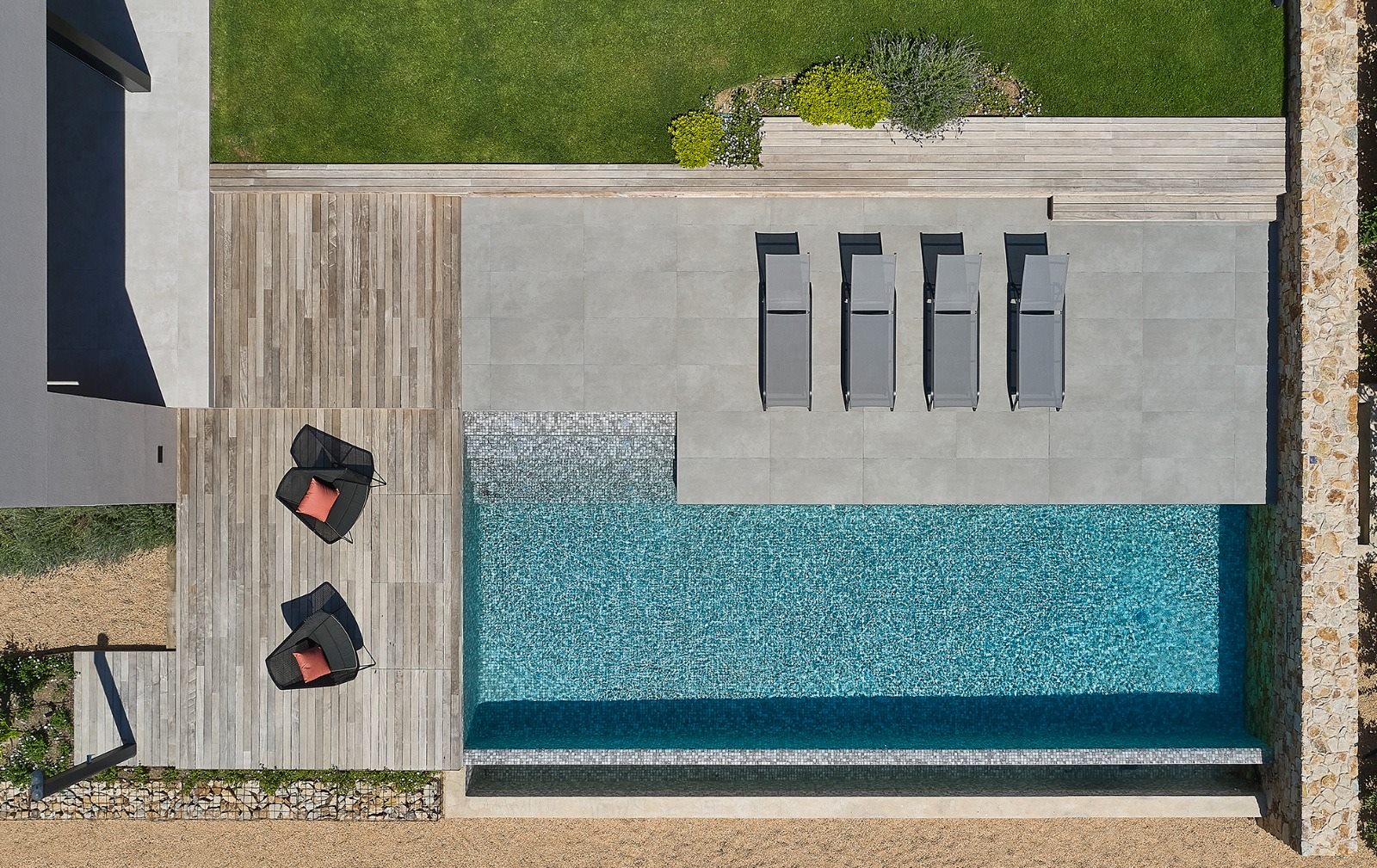 Vista cenital arquitectónica de piscina a medida con solárium de piedra y tarima de madera